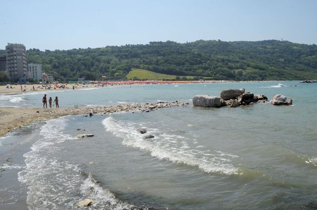 Una spiaggia con onde e persone in lontananza.