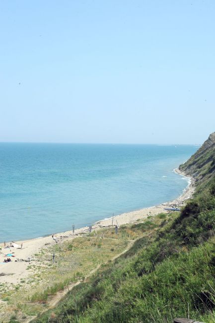 Una spiaggia con mare blu e colline verdi.