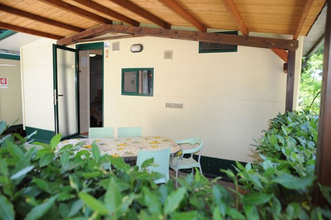 Veranda con tavolo, sedie e ingresso aperto.