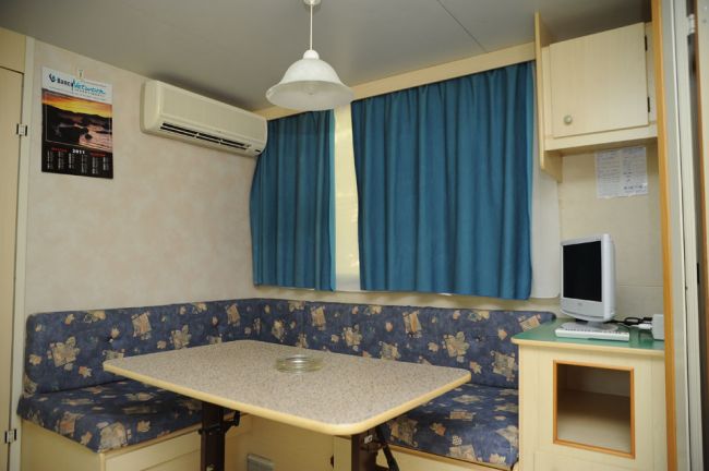Tavolo con sedute imbottite e tenda blu.