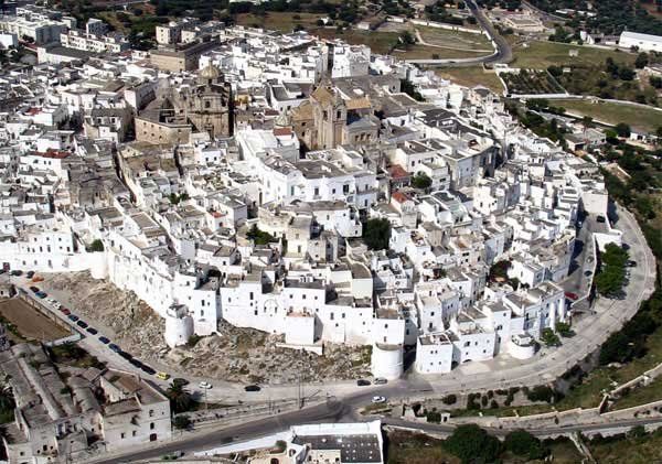Una città storica con edifici bianchi arroccati su una collina.