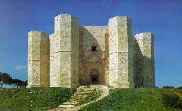 Un castello ottagonale con grandi torri in pietra su un prato verde.