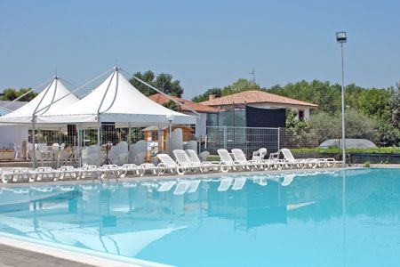 Una piscina all'aperto con sedie a sdraio e tendoni bianchi.