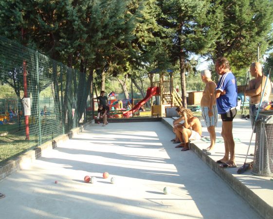 Persone osservano una partita di bocce su un campo all'aperto.