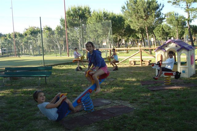 Bambini giocano su altalene a molla in un parco.