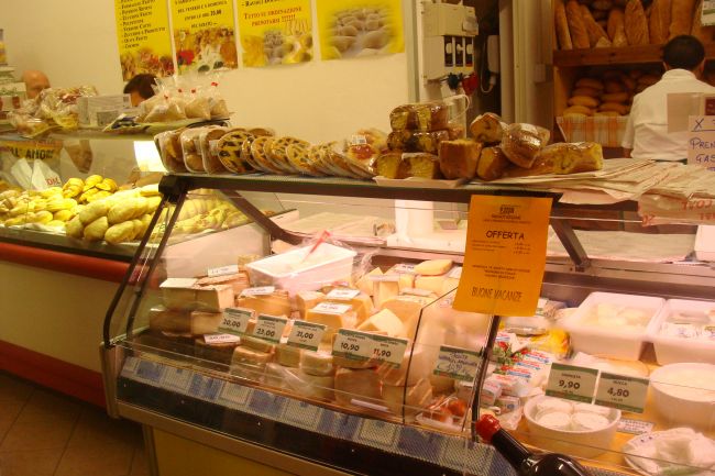 Interno di una salumeria italiana con vetrina di formaggi e prodotti da forno.