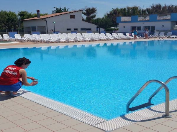 Piscina con un bagnino accucciato vicino al bordo.