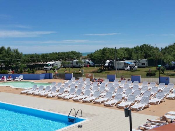 Piscina e lettini, camper sullo sfondo.