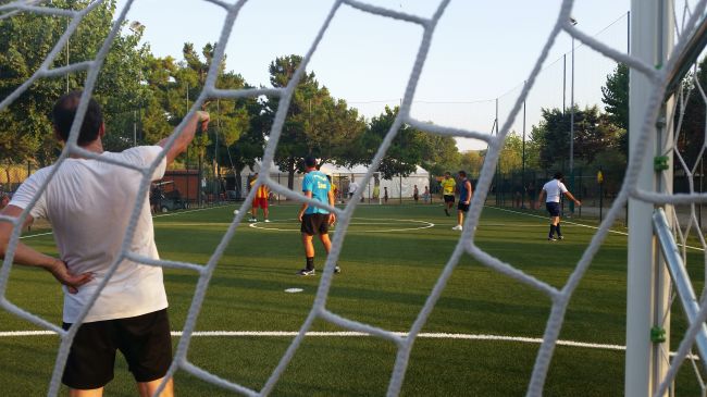 Calciatori su campo sintetico, visto dalla porta.