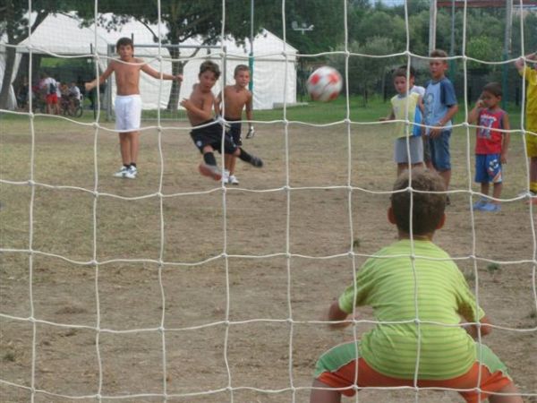 Bambini giocano a calcio, un tiro in prossimità del portiere.