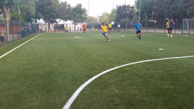Giocatori corrono su un campo di calcio in erba sintetica.