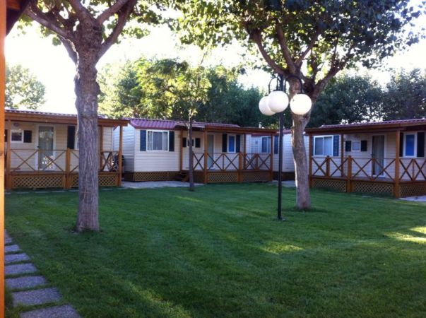 Bungalow con verande, alberi e prato curato.
