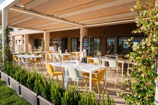 Ristorante all'aperto con tavoli e sedie colorati.