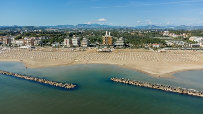 Spiaggia ampia con file di ombrelloni.
