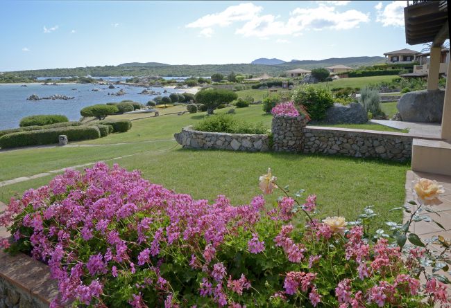 Giardino fiorito con vista sul mare e colline in lontananza.