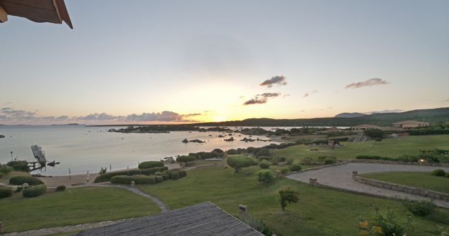 Tramonto su spiaggia rocciosa e prato verde.
