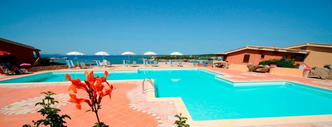 Piscina con vista mare e ombrelloni bianchi.
