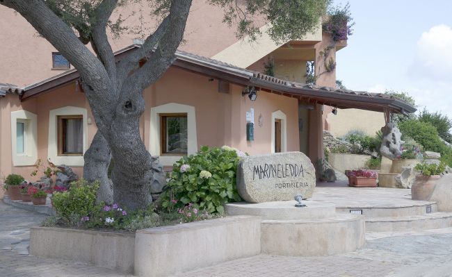 Edificio rustico con albero e pietra con scritta.