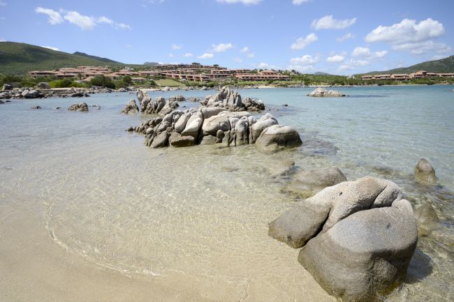 Scogliera con mare cristallino e colline sullo sfondo.