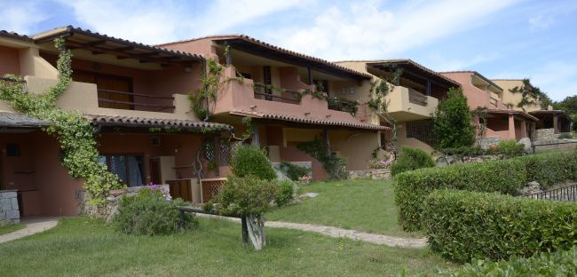 Edifici residenziali con giardino e vegetazione.
