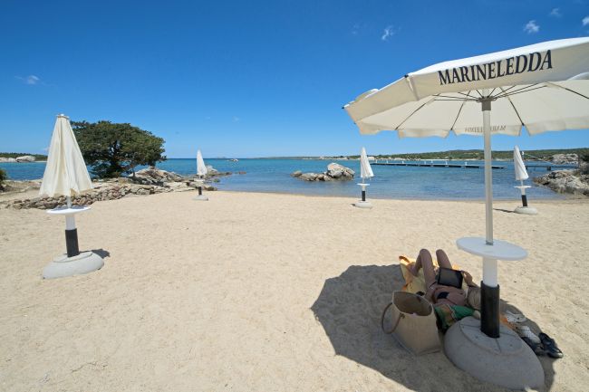 Spiaggia con ombrelloni e persona che riposa.