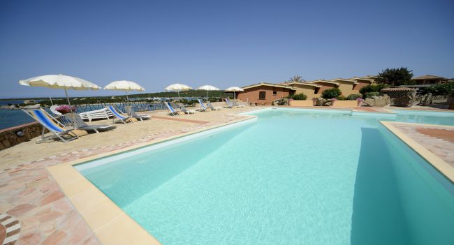 Piscina con lettini e ombrelloni, vista mare.