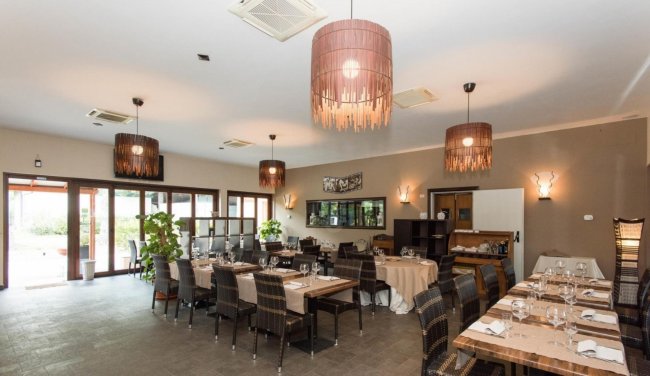 Ristorante elegante con tavoli apparecchiati e lampade pendenti.