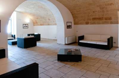Stanza con soffitto ad arco, arredi moderni e pavimento in pietra chiara.