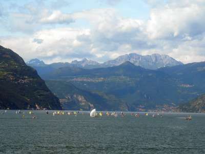 Regata su un lago circondato da montagne con cielo nuvoloso.