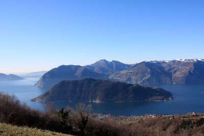 Vista di un'isola verdeggiante in un lago, circondata da montagne.