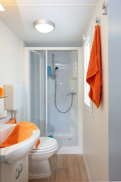 Bagno con doccia e asciugamani arancioni.