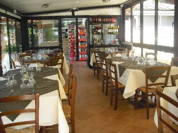 Ristorante con tavoli apparecchiati e scaffali di vini.