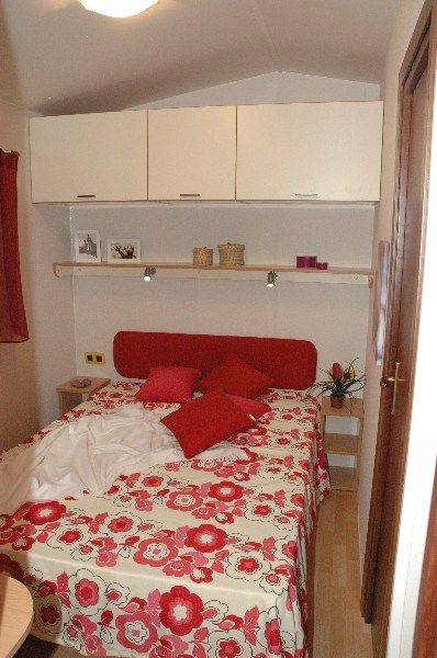 Una piccola camera con letto matrimoniale e mobili bianchi.