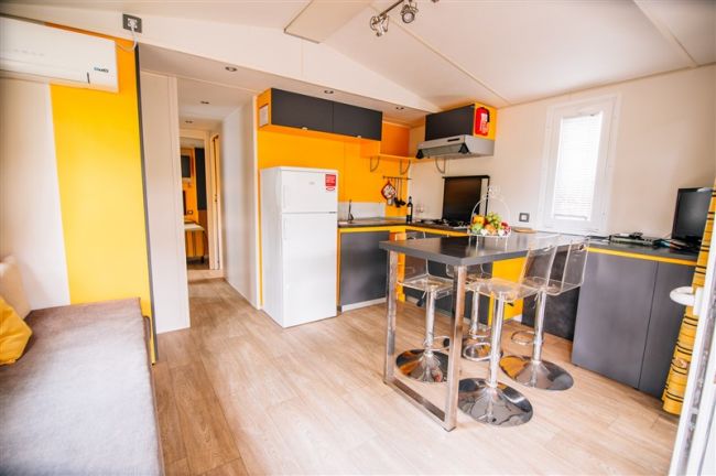 Cucina moderna con mobili gialli e grigi, e un tavolo nero.