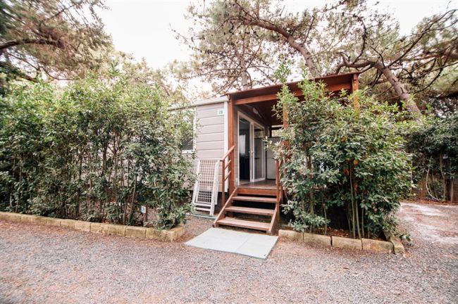Casa mobile con veranda, circondata da alberi.
