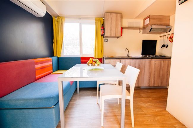 Soggiorno colorato con tavolo, sedie, divano e cucina.