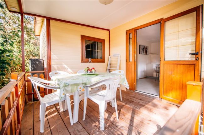 Veranda con tavolo, sedie e porta di legno.