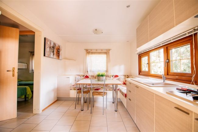 Cucina luminosa con tavolo e finestroni.