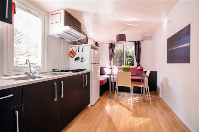 Cucina moderna con zona pranzo e tende scure.