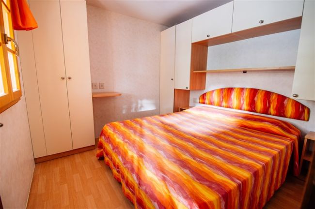 Camera da letto con letto matrimoniale, armadi bianchi.