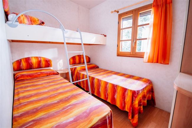 Stanza con letto a castello e letti singoli, copriletto arancioni.