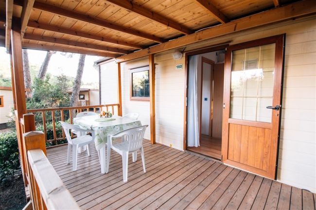 Veranda con tavolo bianco e sedie su pavimento in legno.