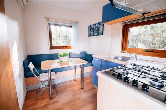Cucina con tavolo piccolo e piante. Divano blu lungo la parete.