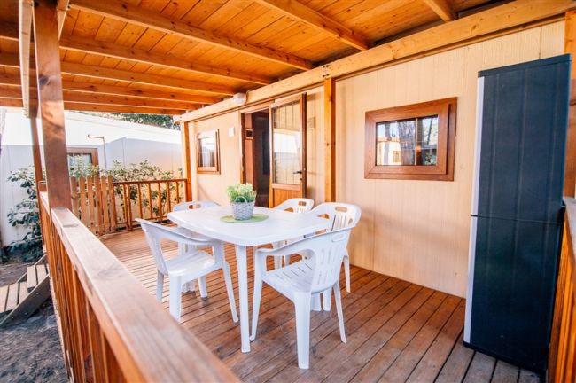 Tavolo bianco con sedie su una veranda in legno.