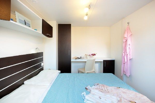 Stanza con letto, scrivania e vestaglia appesa.