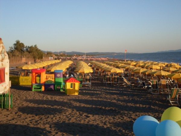 Spiaggia con ombrelloni e area giochi colorata.