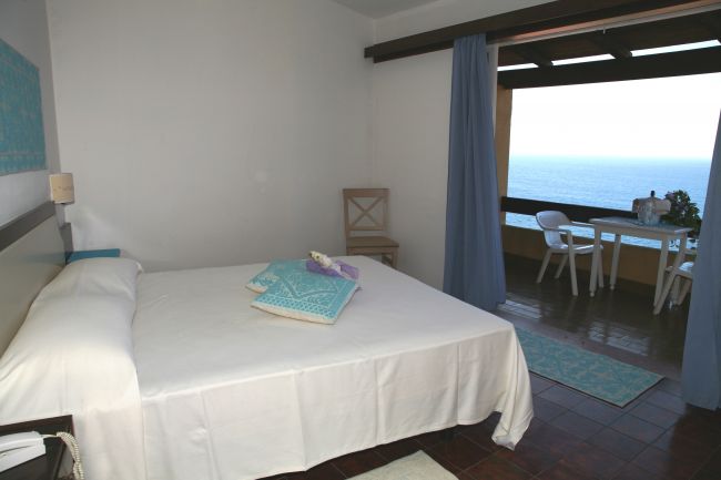 Camera da letto semplice con letto matrimoniale, finestra vista mare.
