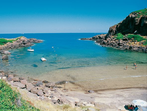 Baia tranquilla con acqua turchese e scogli.
