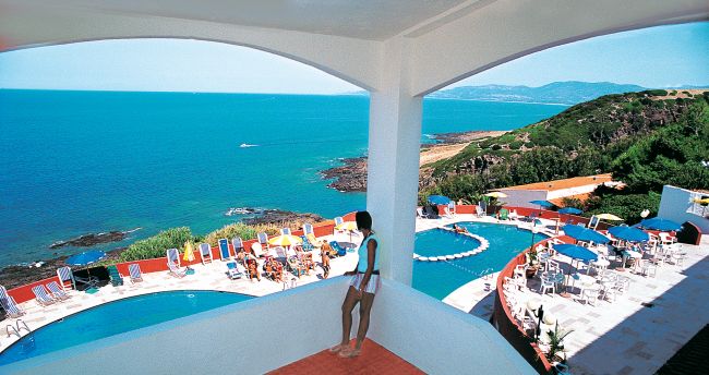Una terrazza con vista sul mare e due piscine all'aperto, circondate da sedie a sdraio colorate.
