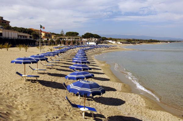 Ombrelloni blu allineati su una spiaggia di sabbia vicino al mare.